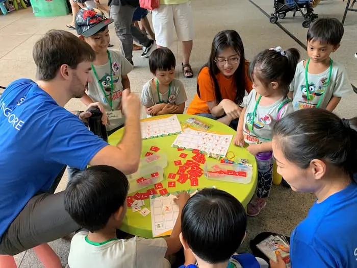 OSF Funded Project: A group of kids and adults playing an educational game on a table, part of the Tiny Thinkers I & II project