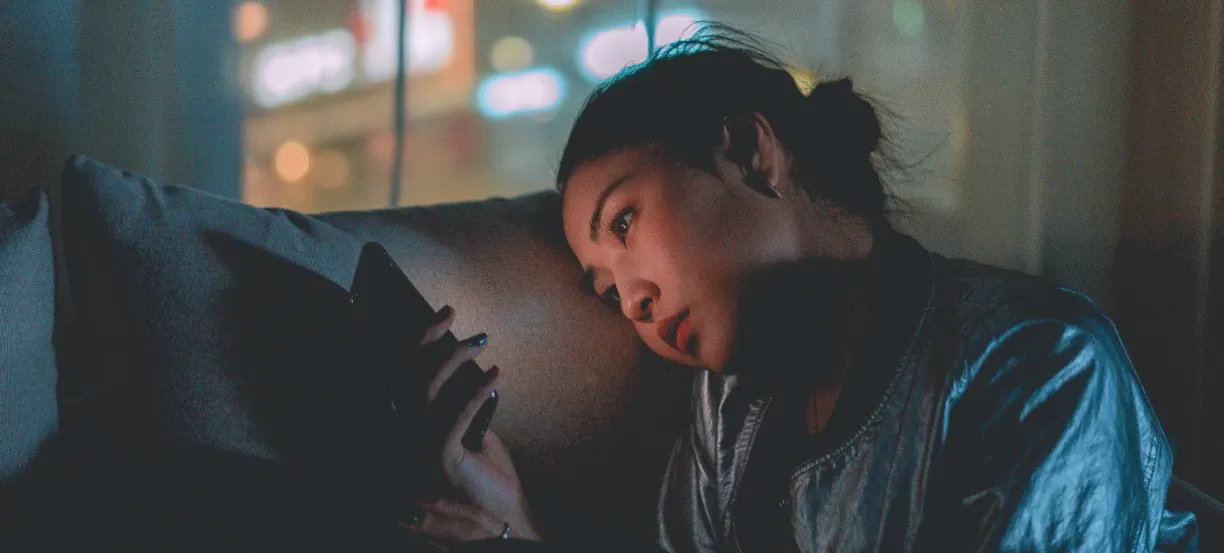 Young woman resting her head on the sofa at night browsing her smart phone